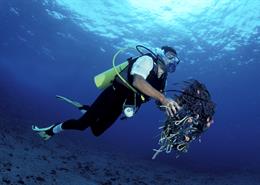 A SCUBA diver removes discarded trash and fishing gear from a coral reef in Brazil.