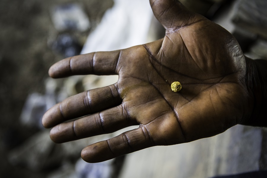 The processing boss holds a small ball of gold dust.